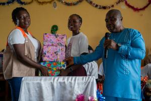 Elizabeth Wreh Sackor, PIH's Liberia’s reproductive health officer (ARSH) and Cyrus K. Wea, statistician at the Ministry of Education Maryland County office, hand over first place gift prize to Mercy T. Hinneh of Cape Palmas Senior High School at the end of the quizzing competition. Photo by Ansumana O. Sesay / PIH 