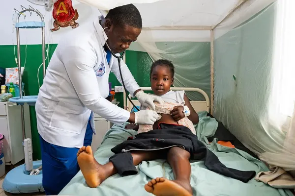 Medical resident Dr. Beyan S. Gweama checks on Prayer Gaye, a patient in the pediatric ward at PIH-supported J.J. Dossen Memorial Hospital in Maryland County, Liberia. Gaye, 8, was diagnosed with acute nephrotic syndrome, a kidney disorder.