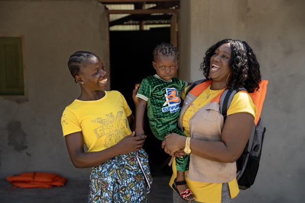 A mother holds her child after the child has been vaccinated during a PIH and CHT community outreach in Liberia