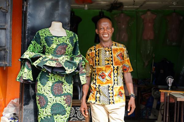 Bobby Togar stands in front of his tailor shop in Monrovia