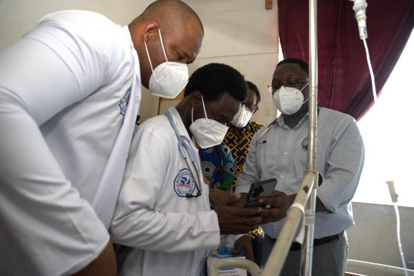 A group of family medicine resident doctors look at the results of a TB patient on an android phone.