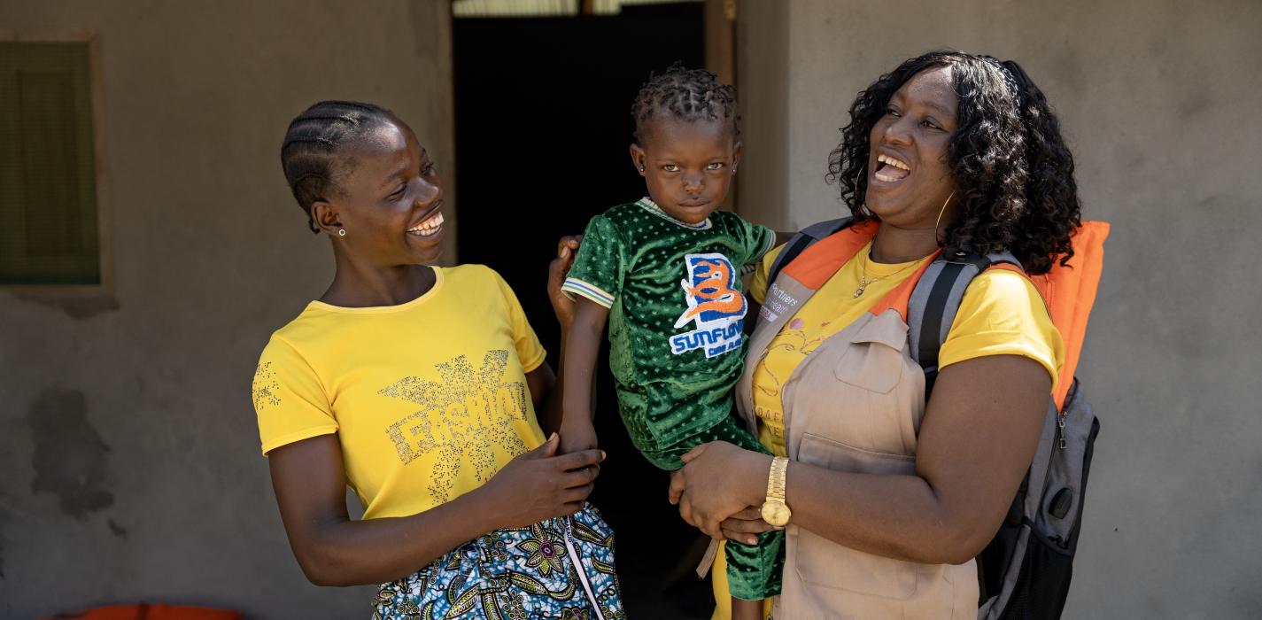 A mother holds her child after the child has been vaccinated during a PIH and CHT community outreach in Liberia