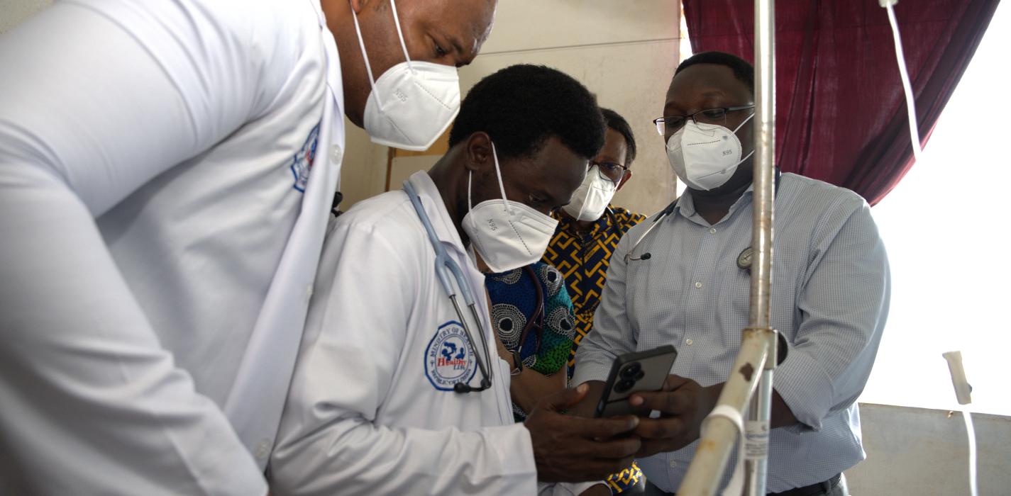 A group of family medicine resident doctors look at the results of a TB patient on an android phone.