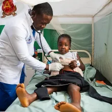 Medical resident Dr. Beyan S. Gweama checks on Prayer Gaye, a patient in the pediatric ward at PIH-supported J.J. Dossen Memorial Hospital in Maryland County, Liberia. Gaye, 8, was diagnosed with acute nephrotic syndrome, a kidney disorder.