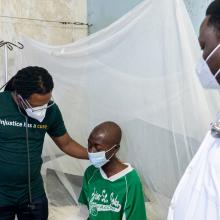 Dr. Maxo Luma, PIH Liberia Executive Director, and Dr. John Paul Otuba, PIH Liberia TB/HIV Lead, with Joe, a 24-year-old carpenter with MDR-TB, receive inpatient treatment at J.J. Dossen Memorial Hospital in Maryland County, Liberia. 