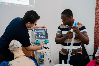 Dr. Paul Sonenthal (left) shows Dr. Beyan S. Gweama (right) how to calibrate the mechanical ventilator. 