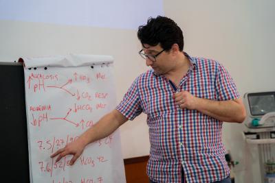 Dr. Paul Sonenthal explains scenarios during a large group presentation with participants at mechanical ventilation training. 